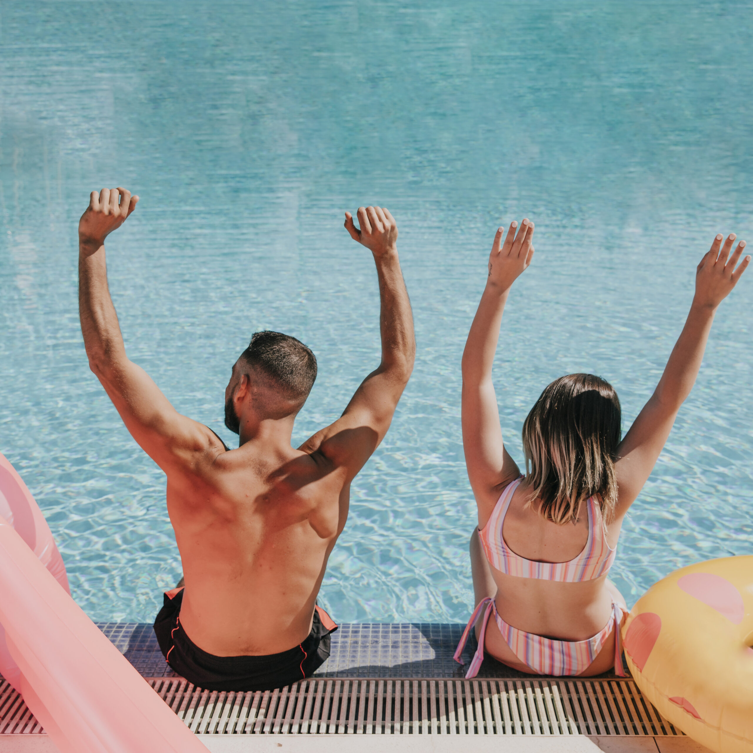couple raising arms pool